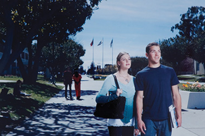 a woman and man standing side by side on a sidewalk.